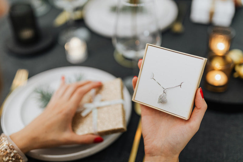 a woman opening a Christmas jewelry gift